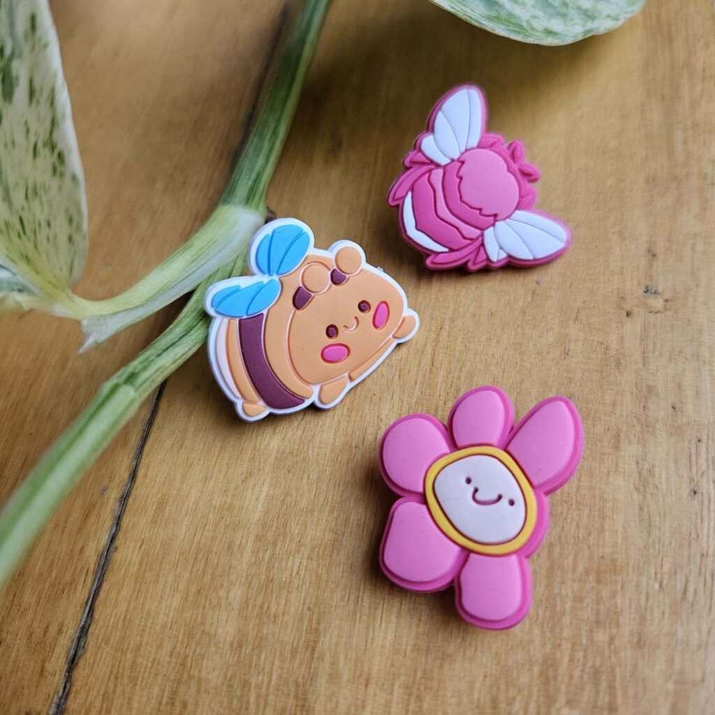 Three Croc Gibbits on a table; two bees and a flower